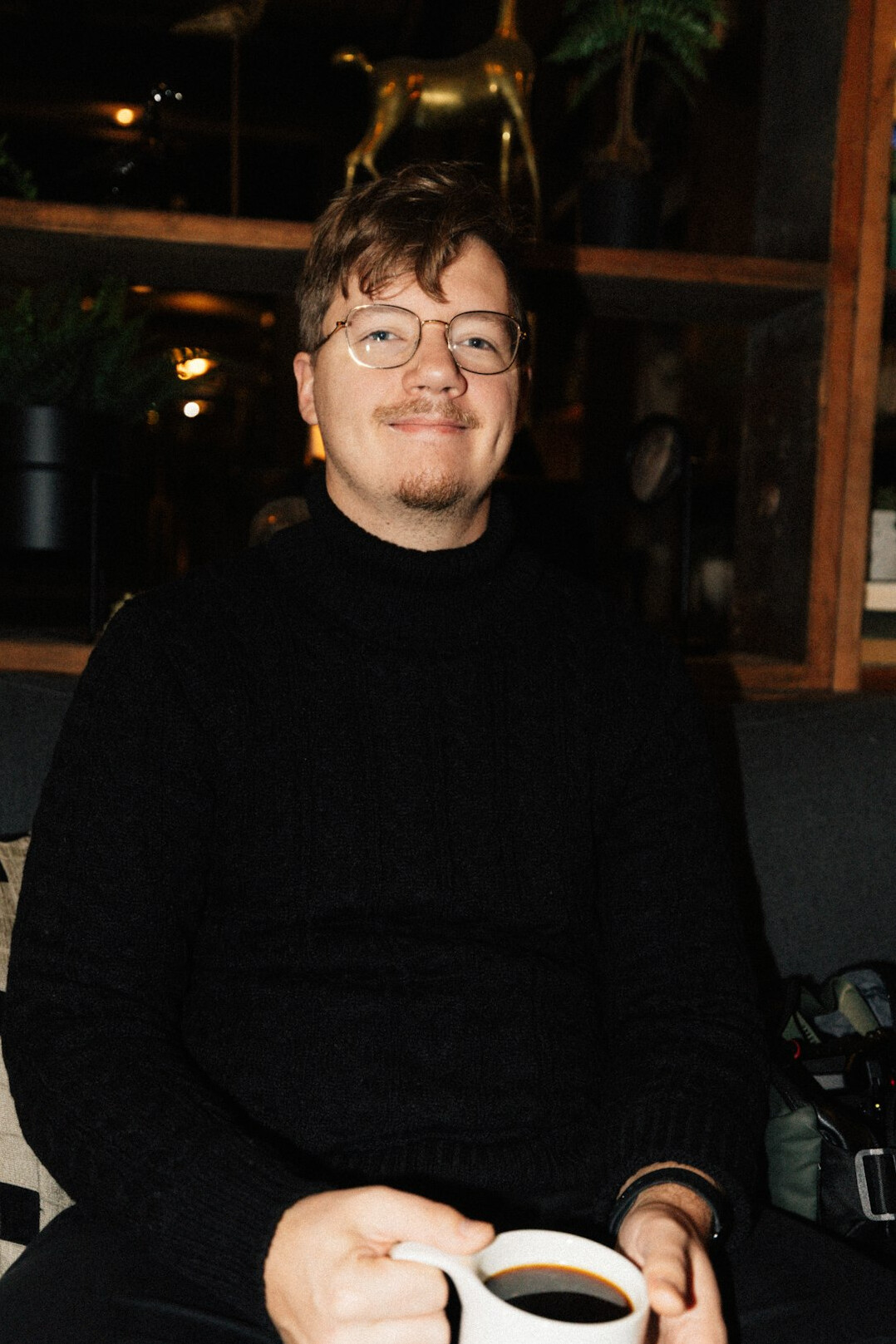 Studio portrait of a man with glasses and a beard in a dark sweater